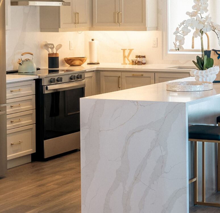 Bright kitchen with a quartz waterfall island, gold hardware and wide-plank floors in a North Hill home